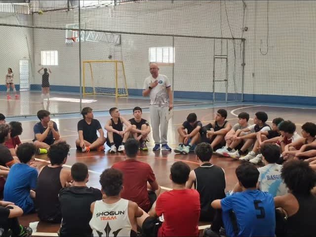 Técnico da Falcons conversando com o grupo de atletas sentados na quadra
