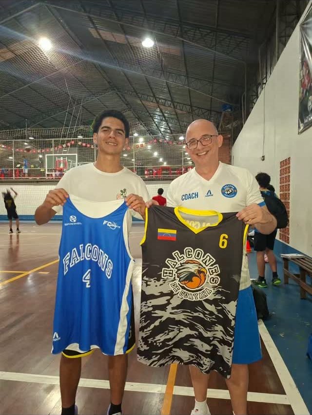 Atleta e técnico da Falcons Basketball com os uniformes da equipe no ginásio